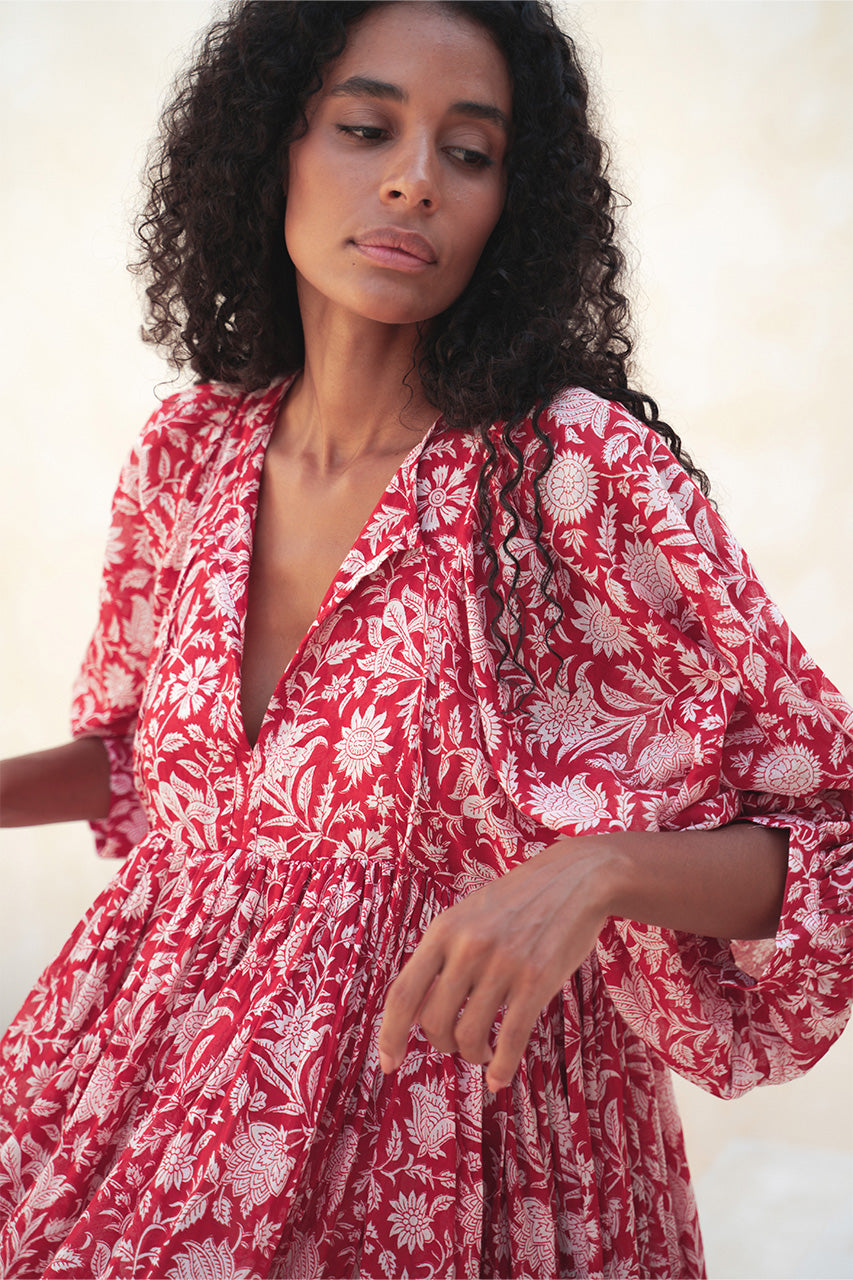 Daughters of India Kyra Midi Dress in Saffron — leaning on sand-coloured wall, floral cotton