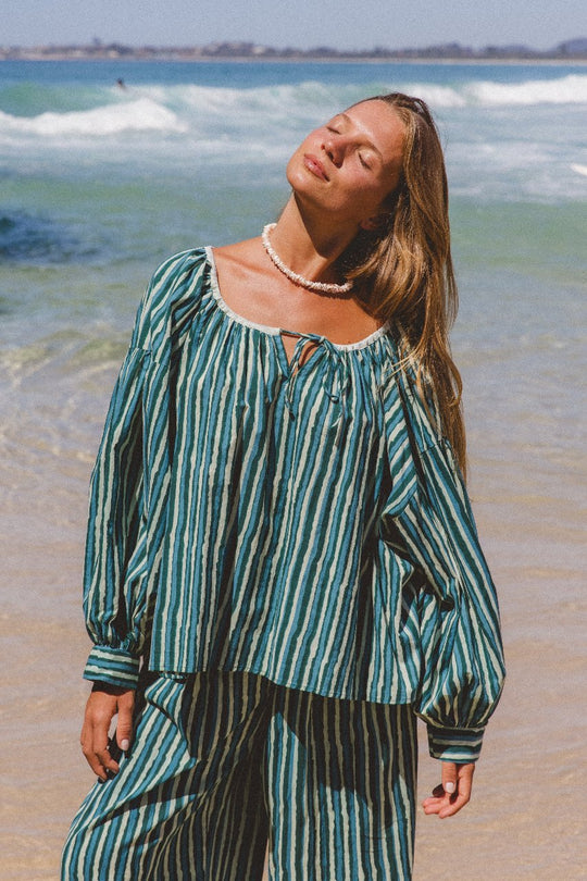 Ria Blouse Cyan Candy — full length front view on sandy beach, model wearing cyan and dark stripe hand block print cotton blouse with relaxed fit, artisan Jaipur India | Daughters of India