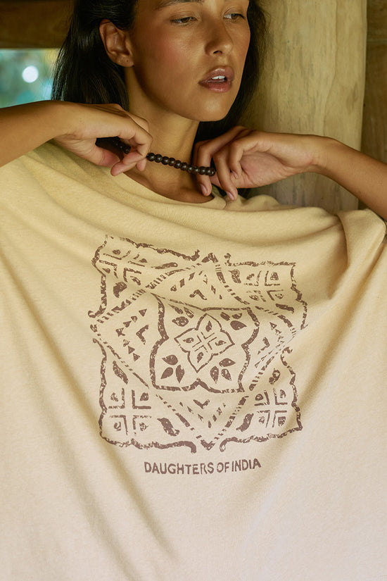 Close-up detail of the Daughters of India block print design on the Shanti Tee in Cashew, showing geometric floral pattern and brand text